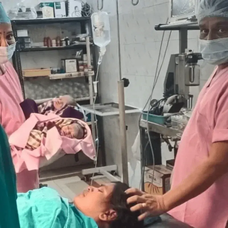 The clinical team in theatre with newborn twins, one attending to the mother after delivery